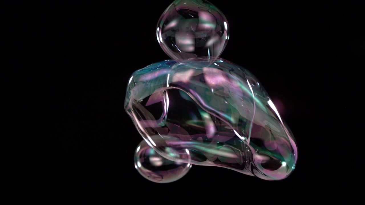 Highspeed Slowmotion captures multiple iridescent soap bubbles drifting colliding and forming changing clusters on black