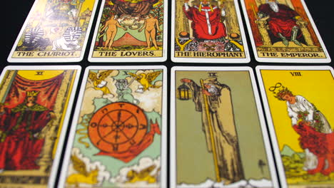 Tarot cards are spread across a surface, showcasing Major Arcana illustrations in vibrant detail. The top-down view highlights intricate artwork and symbolic designs on the deck