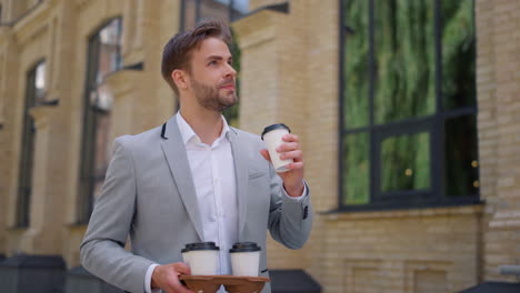 man carrying paper cups with hot coffee to office