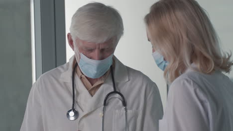 a pair of doctors with masks converse while looking at results