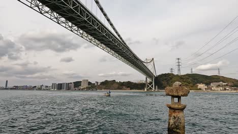 old japanese rock lantern halfly submerged in water in front of kanmon bridge and the kanmon strait in between the japanese island honshu and kyushu