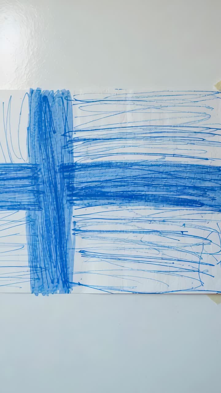 Vertical video: Recording camera filming large white paper taped on wall, showing blue marker bands