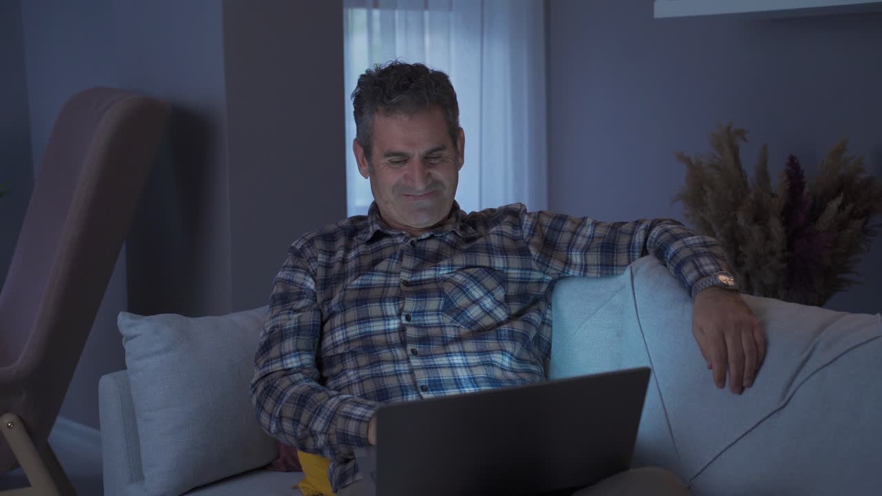 hombre sonriente mirando la computadora portátil en casa y feliz.