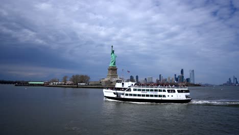 statue of liberty island with statue city cruises boat ferry passing by, wide