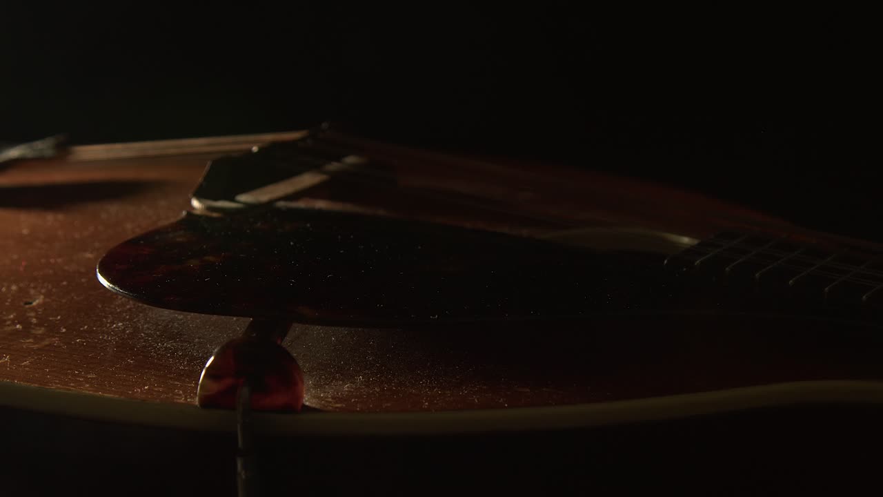 La luce accarezza le corde e il battipenna di un mandolino vintage impolverato