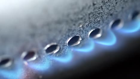 burning gas burner in the oven close-up on a black background. 4k extreme close-up raw video with smooth camera movement.