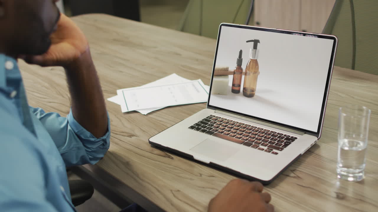 Uomo afroamericano al tavolo che usa il laptop, fa shopping online per prodotti di bellezza, al rallentatore.