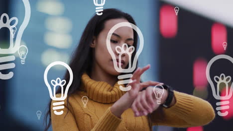 Animation-of-lightbulbs-over-biracial-woman-using-smartwatch