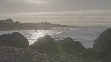 big waves crashing on the beach near reve havn borestranda norway during sunset with the beach and sea in the background and the sun reflection in the water with rocks in the foreground log