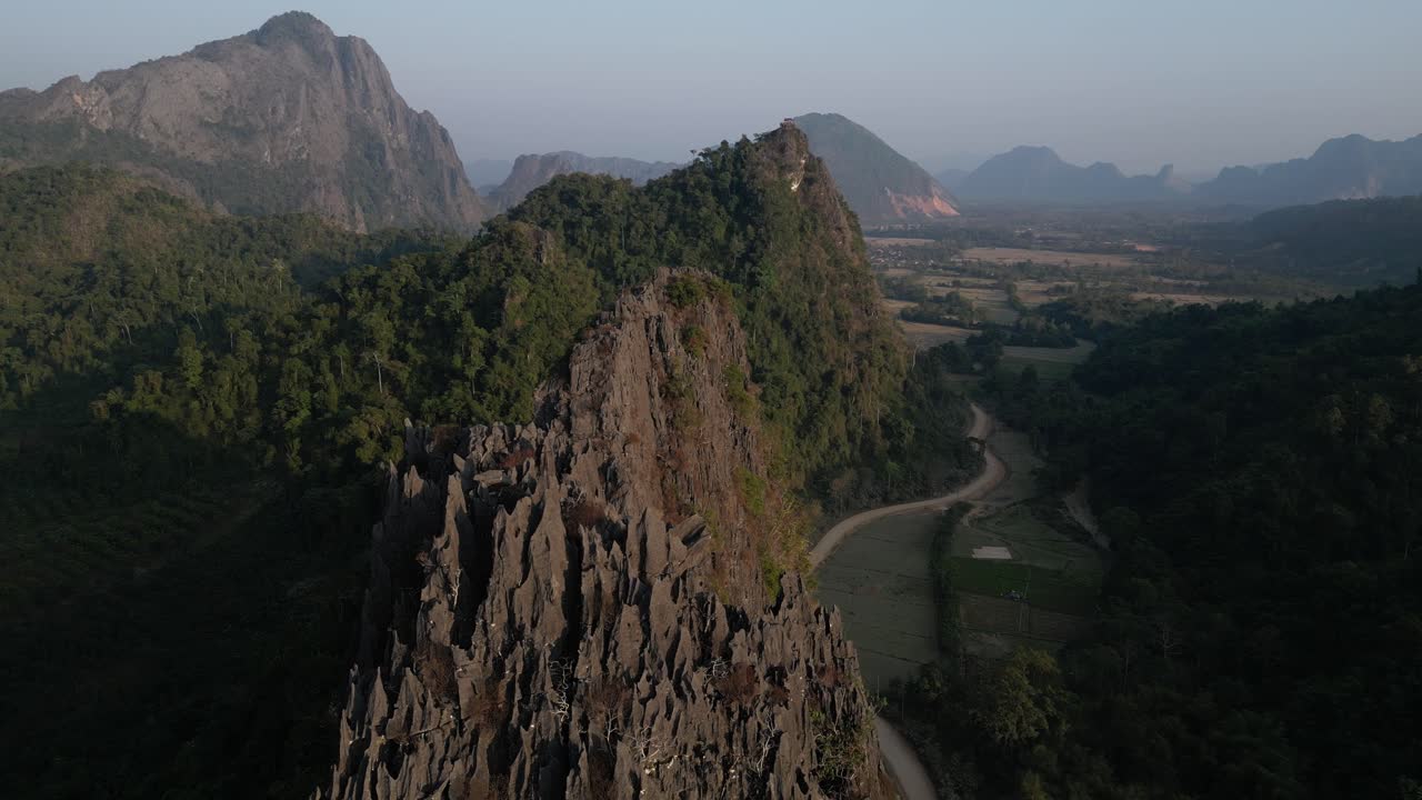 tomada de un avión no tripulado de acantilados dentados y carreteras rurales en vang vieng, la capital de la aventura de laos