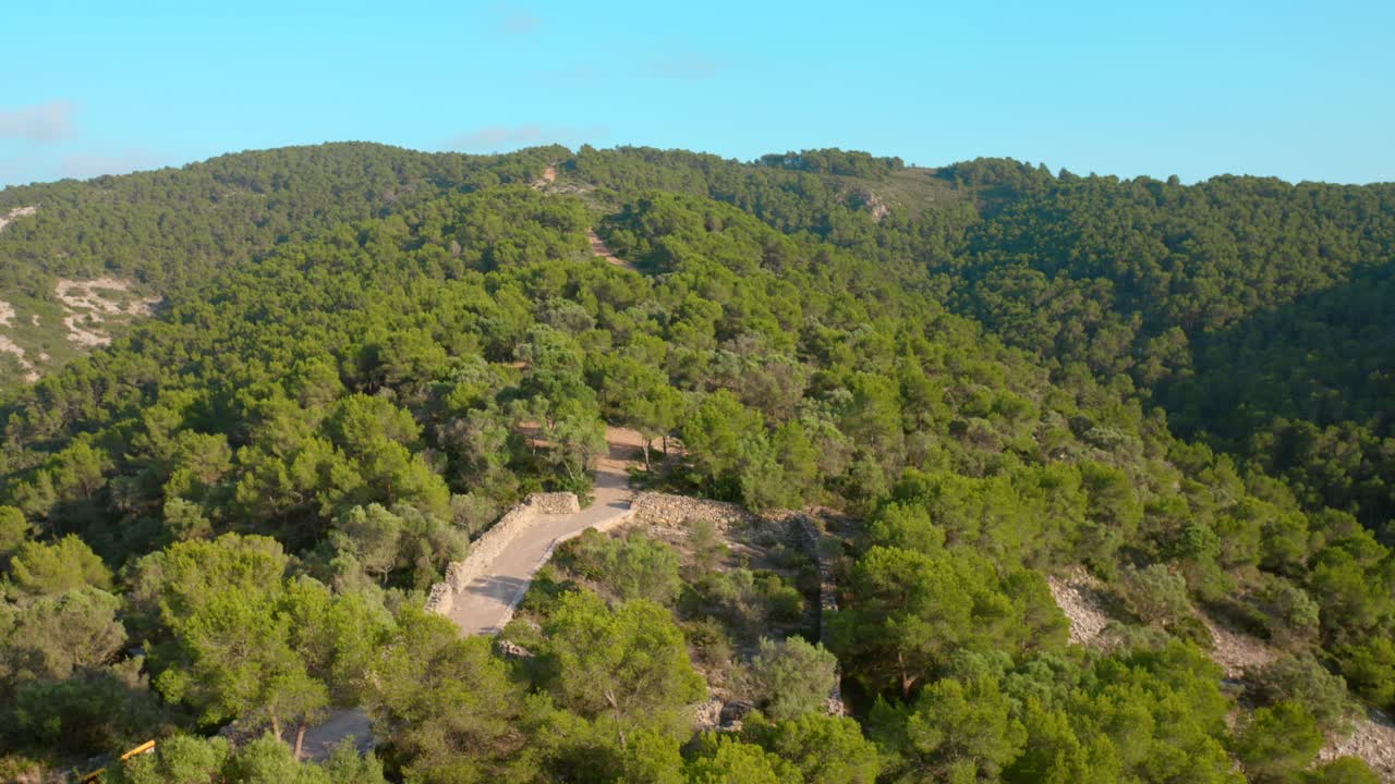 Aerial drone shot over green vegetation covering hilly terrain in Serra d'Irta natural park, Costa del Azahar, Spain at daytime