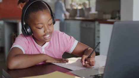 Happy-diverse-mother-with-daughter-learning-with-laptop-in-kitchen-in-slow-motion