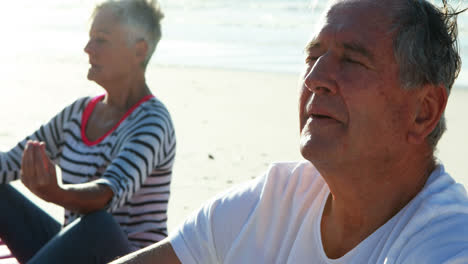 Senior-couple-doing-yoga-at-beach