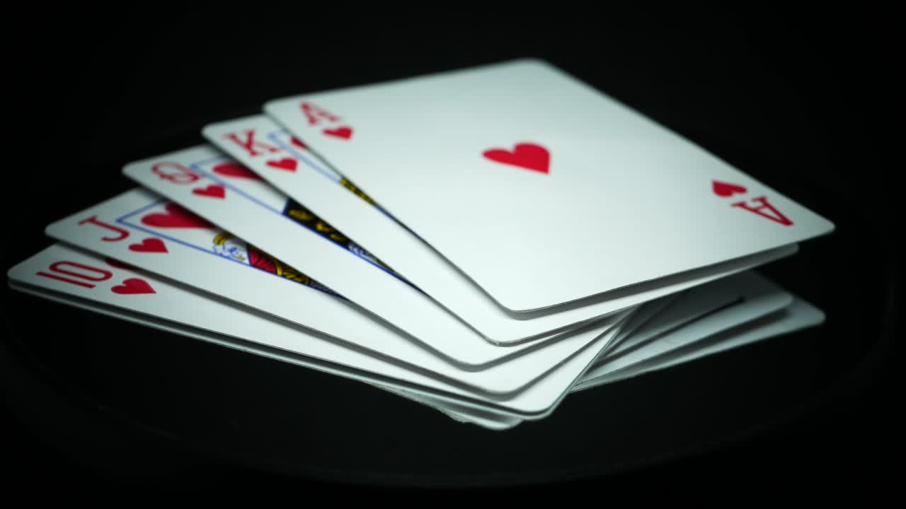 Royal Flush Of Hearts Rotating On Reflective Surface In Black Background - close up, studio shot