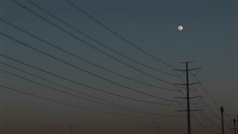 mediumshot of the moon high above powerline