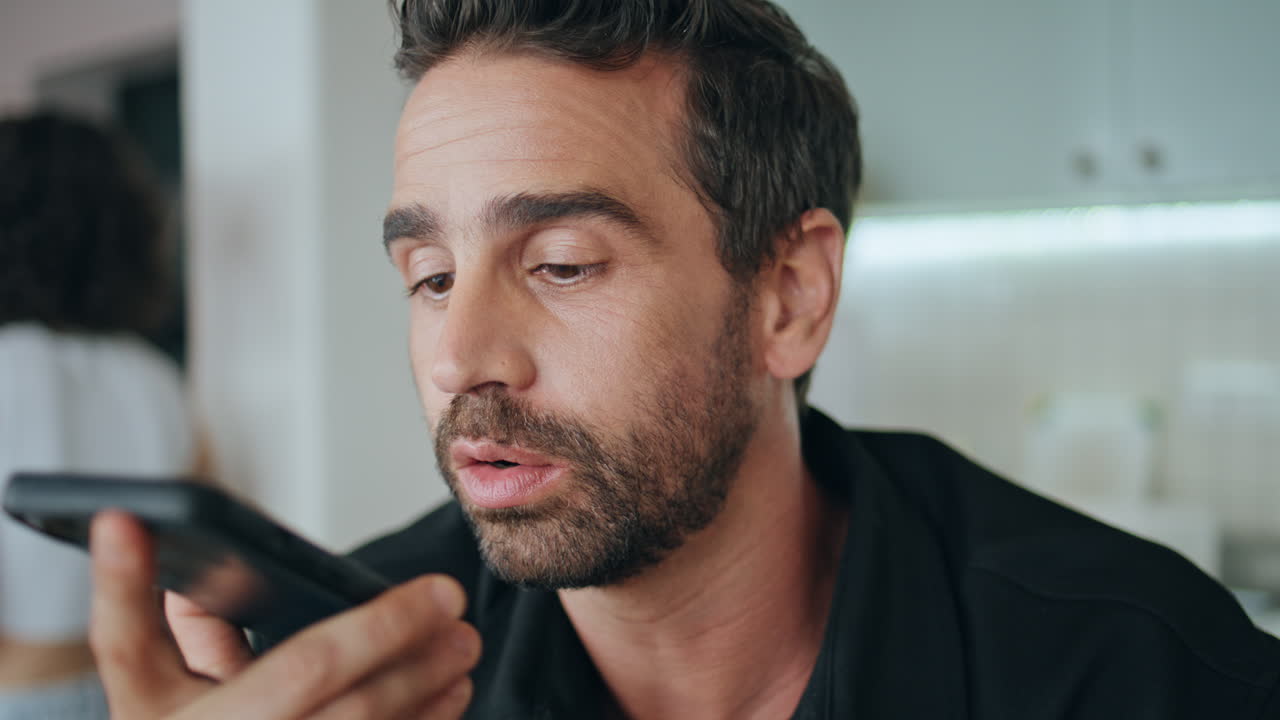Ritratto di un uomo che registra un messaggio vocale con lo smartphone, seduto in un piccolo ristorante.