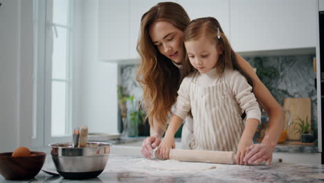 cute mom child rolling dough out indoor closeup. mother daughter kneading pastry