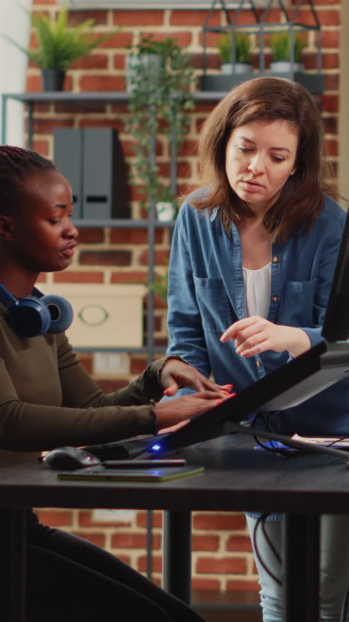 Vertical video: Multiethnic group of 3d artists developing digital interface in production agency