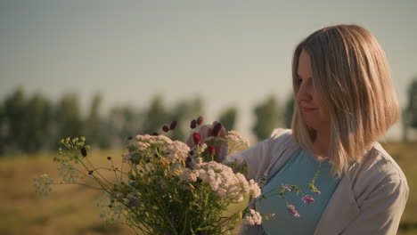 smiling gardener arranging fresh flowers in picturesque farmland with distant trees in background under bright clear sky, serene setting captures tranquility of countryside and the joy of gardening