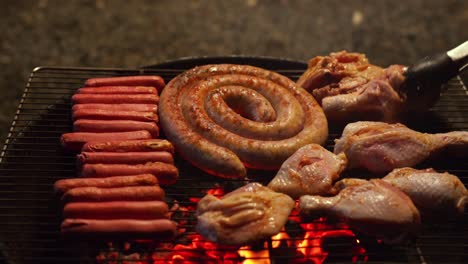 Grillen-Mit-Würstchen-Und-Hühnchen,-Mann-Dreht-Hühnchenstücke-Auf-Den-Grill,-Abendliches-Treffen-Zu-Hause-Mit-Familie-Und-Freunden