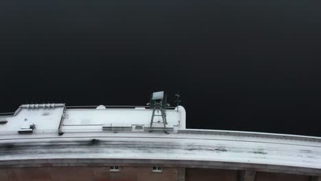 Torre-De-Vigilancia-En-La-Parte-Superior-De-Una-Presa-En-Invierno-Con-Un-Camino-Nevado-En-Una-Mañana-Fría,-Vista-Aérea-Giratoria-Desde-Un-Dron