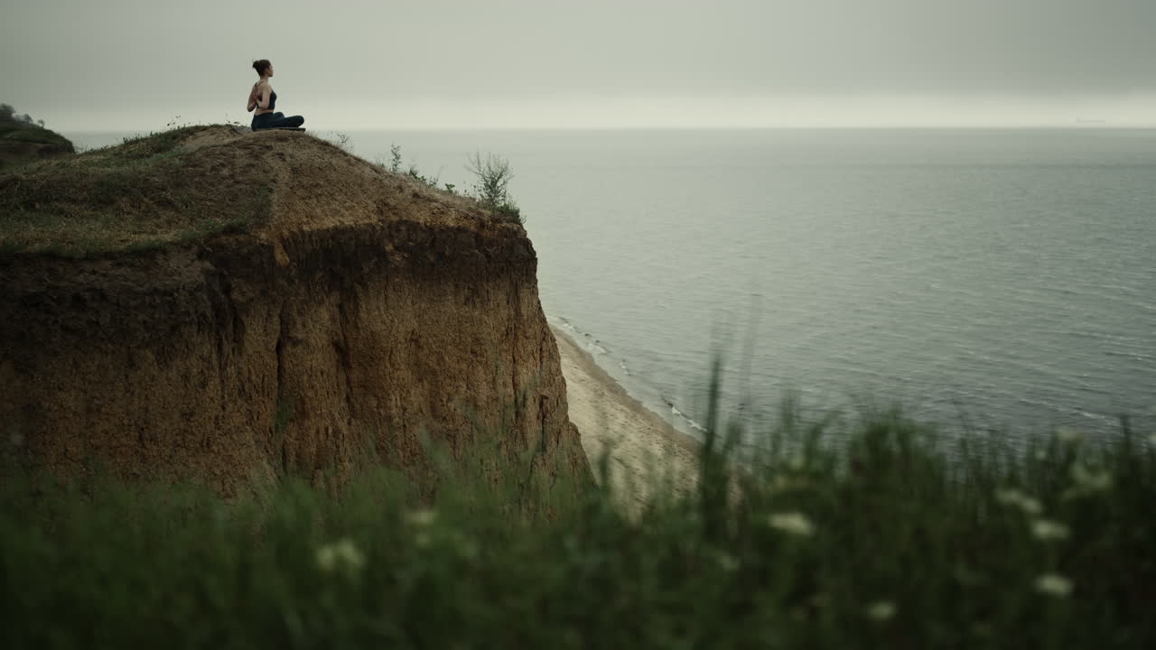 로터스 자세로 앉아 있는 소녀는 손을 등에  ⁇ 고 있습니다. 요가 아사나를 하는 여성.