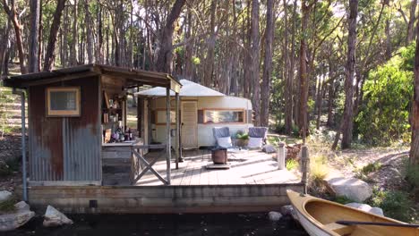 a tiny house on a lake with a boat, set in a beautiful forest, australia