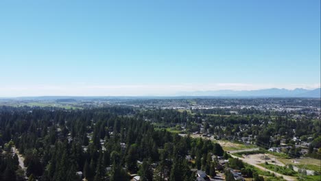 a peaceful aerial view of a developing neighbourhood in surrey, bc with houses nestled amongst lush green scenery and majestic mountain ranges