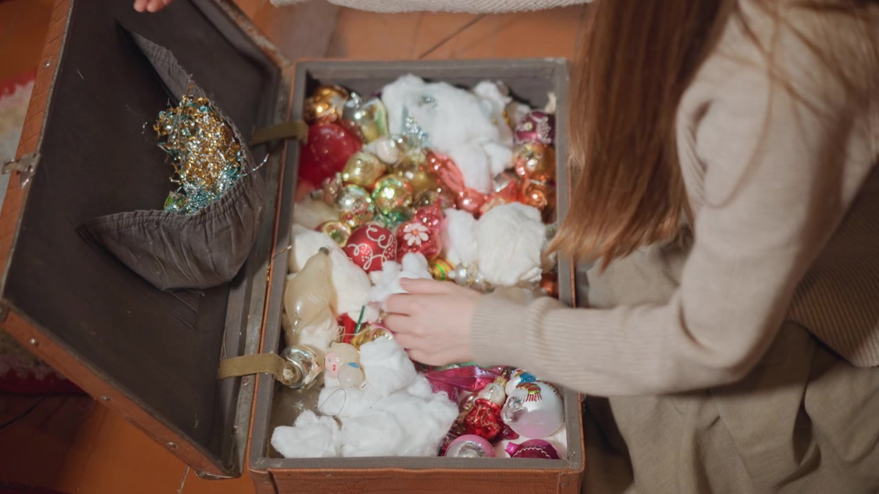 Caucasian woman sorting heirloom ornaments in vintage trunk soft light, cotton fillers, wooden floor and round rug frame intimate conservation moment careful conservator role as she organizes