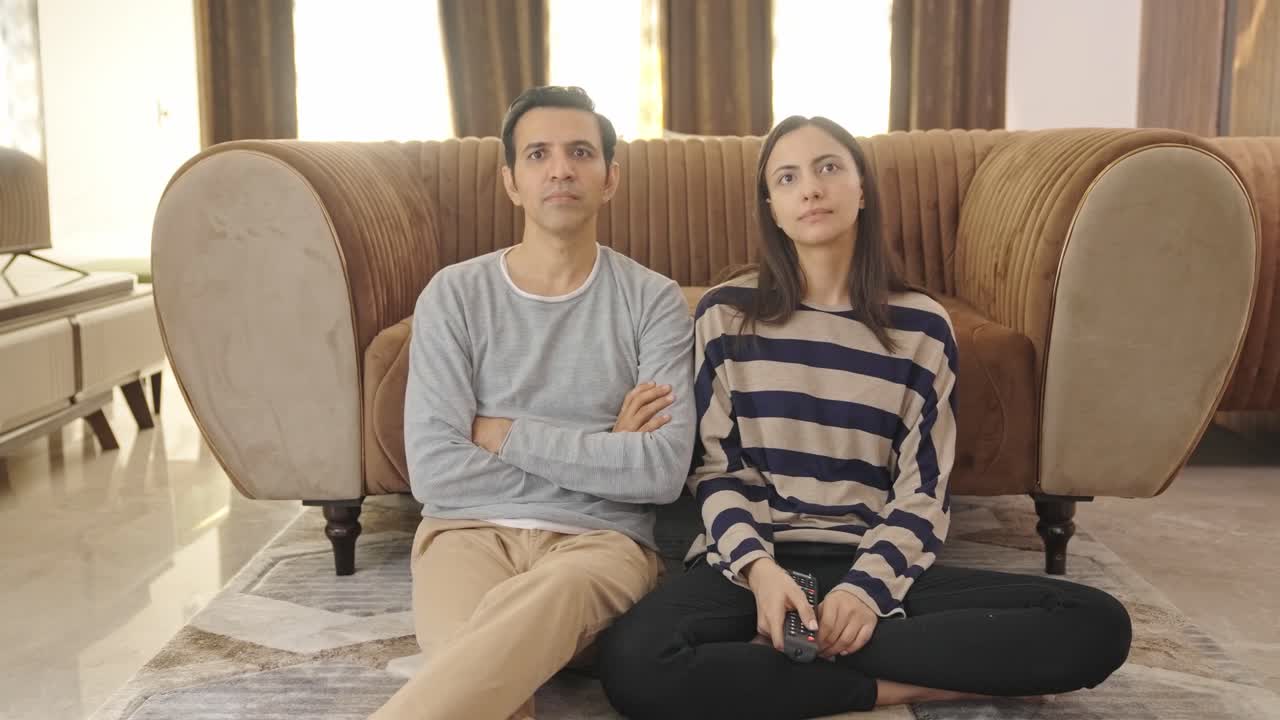 겁에 질린 커플이 tv에서 충격적인 뉴스를 듣습니다.