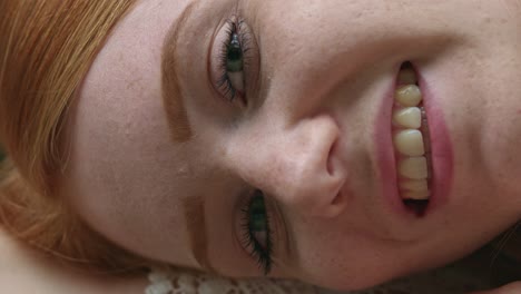 close-up highly-detailed portrait of amazing young redhead female model with green eyes and clean healthy skin with lots of freckles, looking at camera with a smile