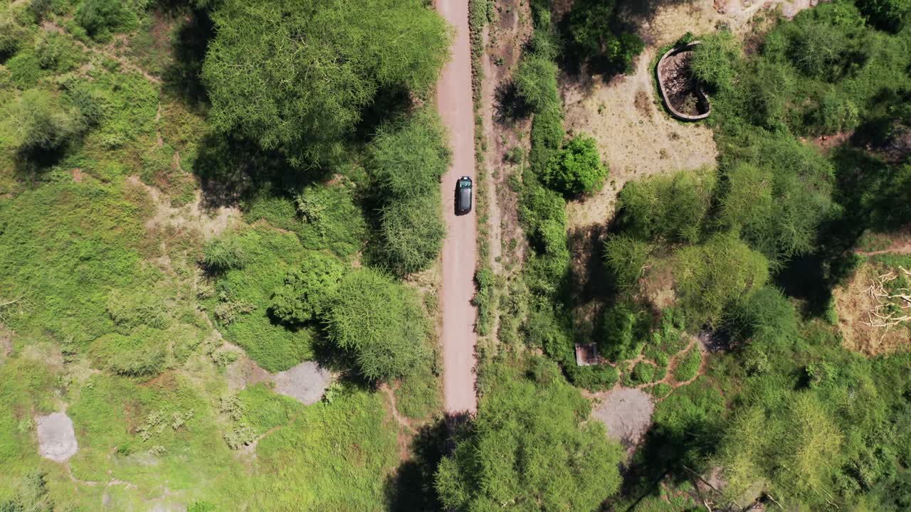 Aerial top down shot following a van driving in a gravel road in Tanzania