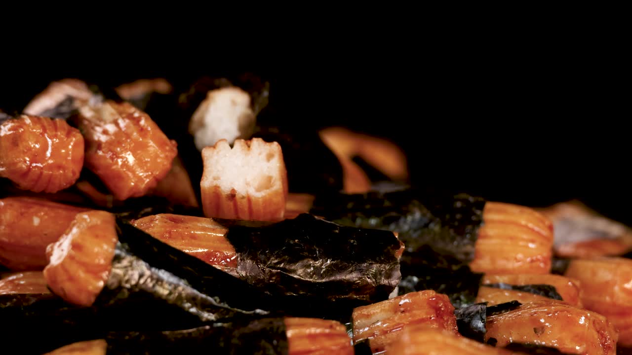 Macro shot of crunchy rice crackers with seaweed, slow rotating camera, dramatic dark background