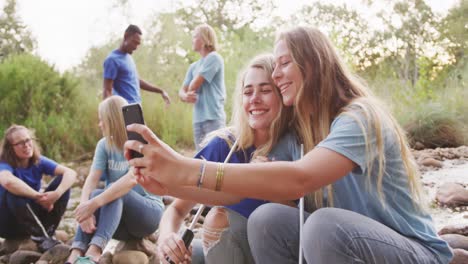 Mid-adults-volunteering--and-women-taking-a-selfie-during-river-clean-up-day