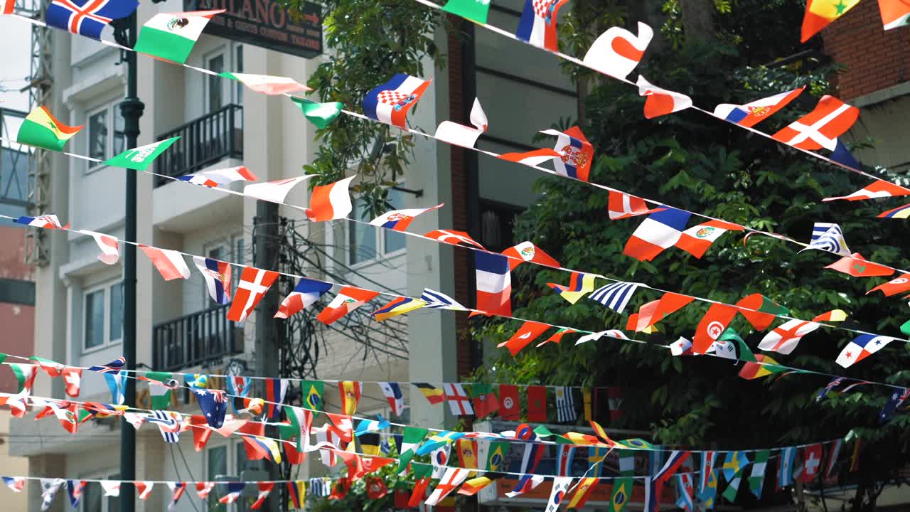 Flags of many countries hang on ropes in the air at the city background