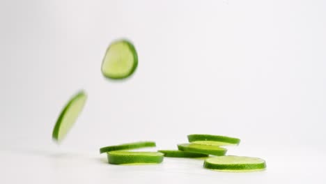 fresh green lime slices falling onto white table top, bouncing and landing in a pile in slow motion