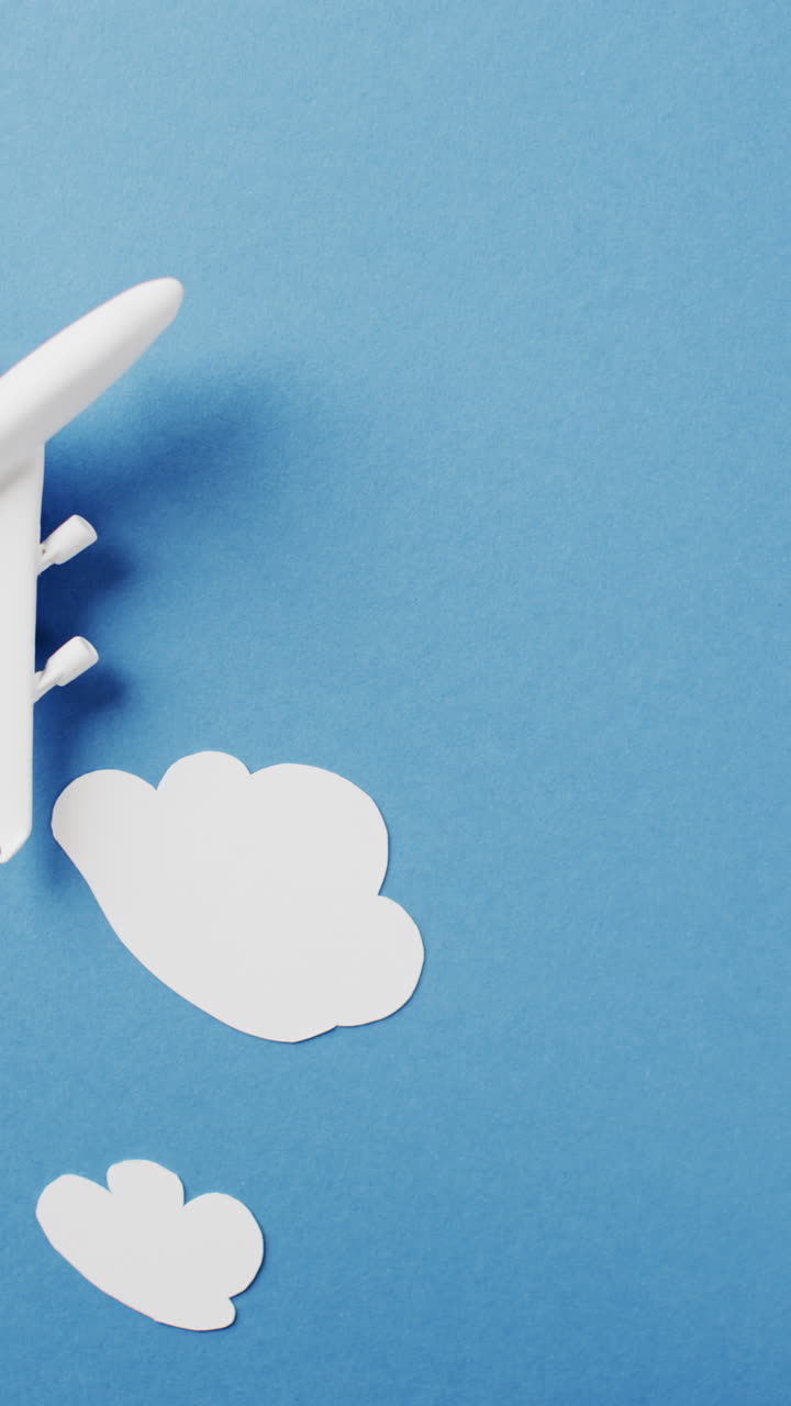 Vertical video of white airplane model with white clouds and copy space on blue background