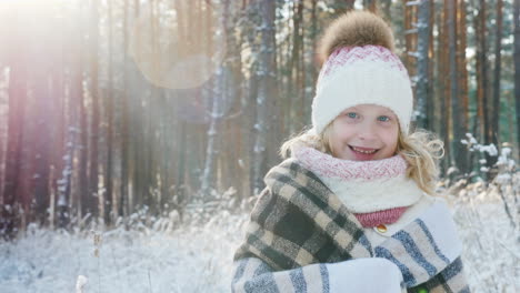 Porträt-Eines-Glücklichen-Kleinen-Mädchens,-Eingehüllt-In-Ein-Plaid-In-Einem-Verschneiten-Winterwald