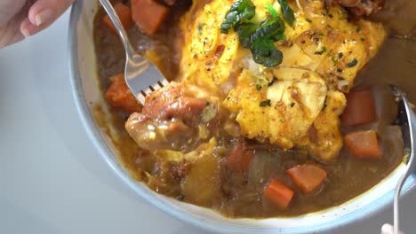 cinematic point of view of dining experience, a person using fork to eat delicious japanese omurice, dipping crispy karaage fried chicken in the curry sauce, overhead close up shot