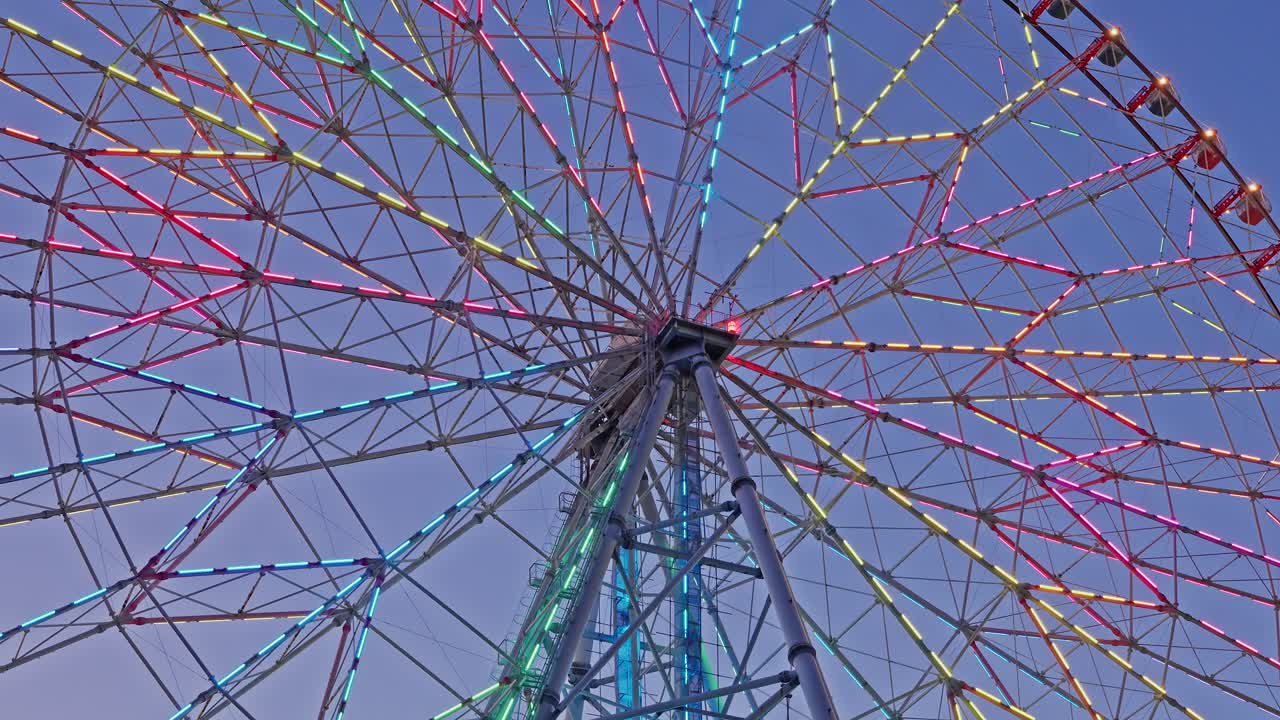 A dynamic close-up of the Diamond and Flower Ferris Wheel's spokes with multi-colored LED lights at twilight