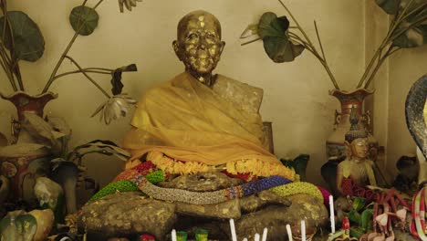 statue of old monk with snakes and lotus flowers in a thai buddhist temple