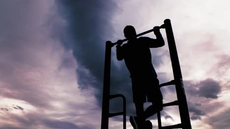 powerful black silhouette outline of a male doing pull ups or chin ups against a dramatic sky