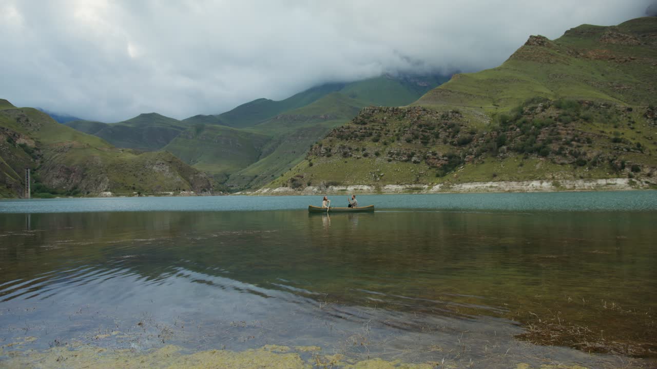 산의 호수 에서 카누 를 타고 있는 부부