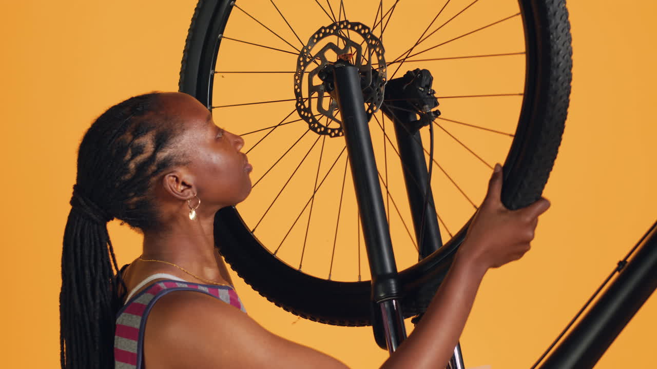 mujer desmontando la rueda de la bicicleta y ajustando el manillar, fondo del estudio