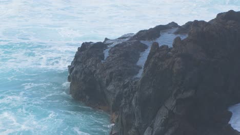 A-big-waves-of-the-Atlantic-Ocean-breaks-on-a-rocky-coast-on-a-sunny-day-during-a-storm-in-Puerto-de-la-Cruz-in-the-Canaries-,-medium-handheld-shot