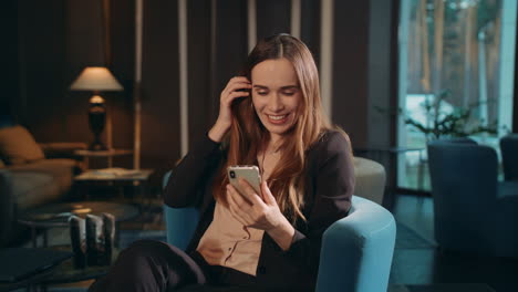 mujer feliz usando un teléfono inteligente para una llamada de video en línea en el salón del hotel