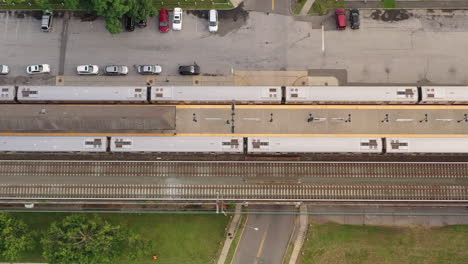 a top down shot directly over a railroad train station with one train stopped and another pulling out of the station