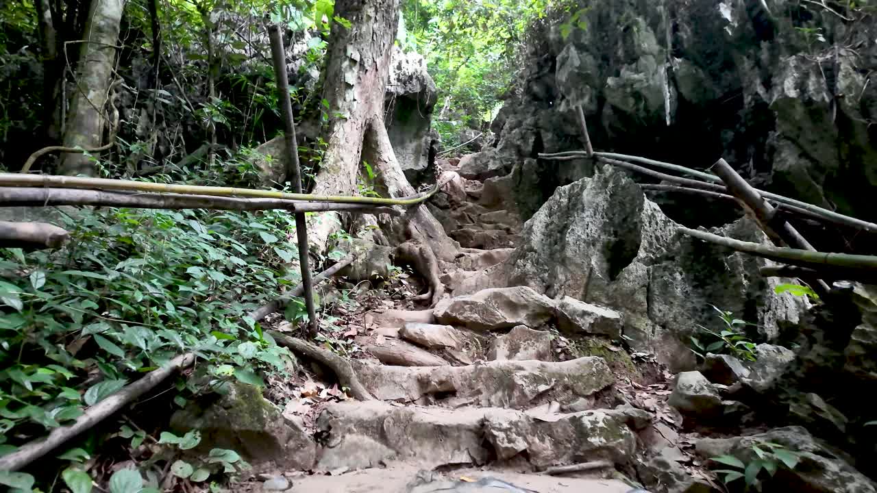 Tham Phu Kham Cave trail in Vang Vieng Laos featuring stone steps lush greenery and bamboo railings
