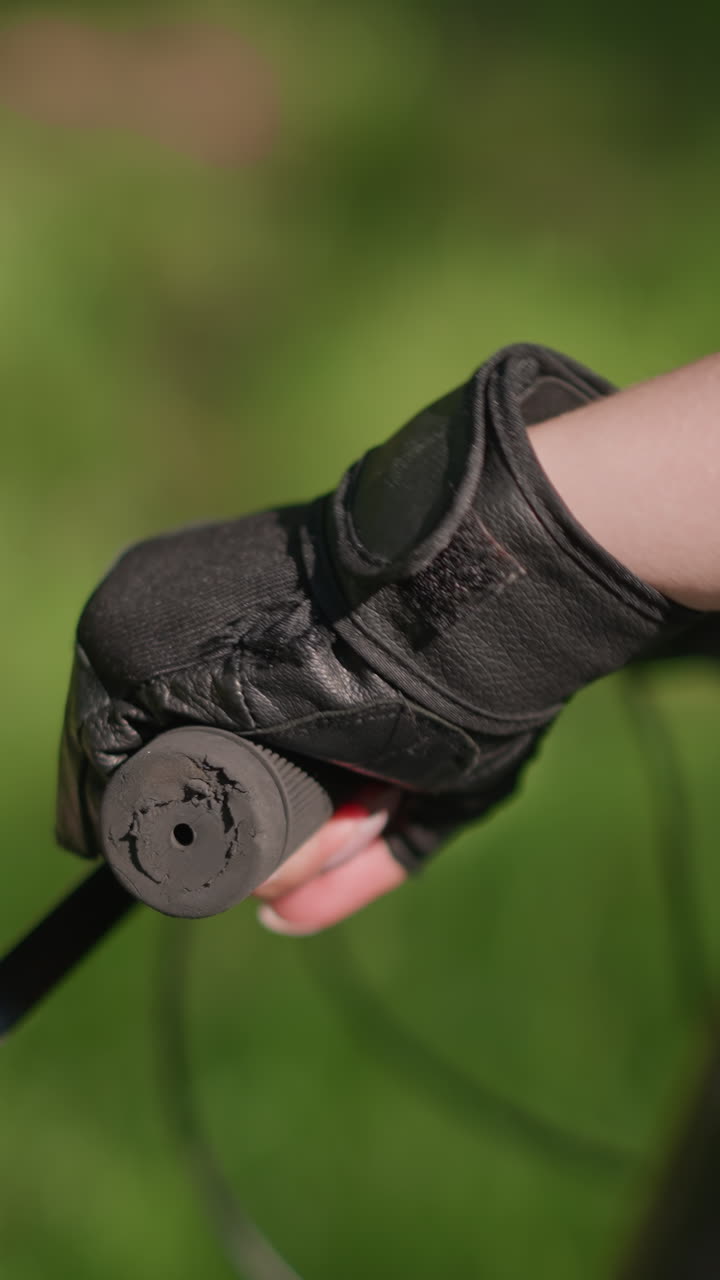 primer plano del manillar de la bicicleta individual con la mano en guante, el acelerador y el freno en uso, la luz del sol se refleja suavemente en el guante, creando una escena enfocada contra un fondo verde suavemente borroso