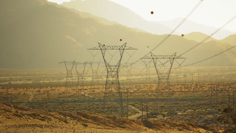 Steady-view-looking-down-huge-high-voltage-transmission-lines-and-supply-grid-near-Palm-Springs-in-the-Mojave-Desert,-California,-USA